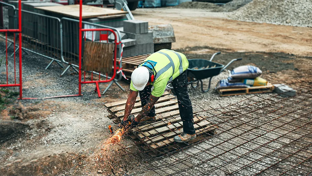 Help keep employees safe on the job with affordable workers’ comp insurance. A person wearing hard hat and other protective gear working on metal with sparks flying. 