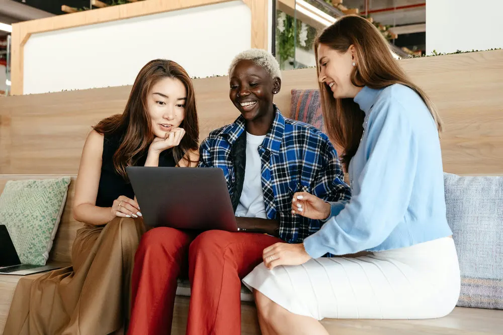 Three employees sit together to review affordable healthcare solutions for small business on laptop.