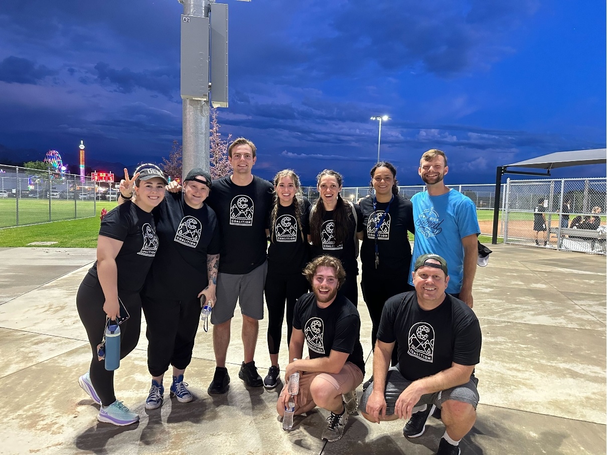 Coalition employees posing on softball field during a team outing.