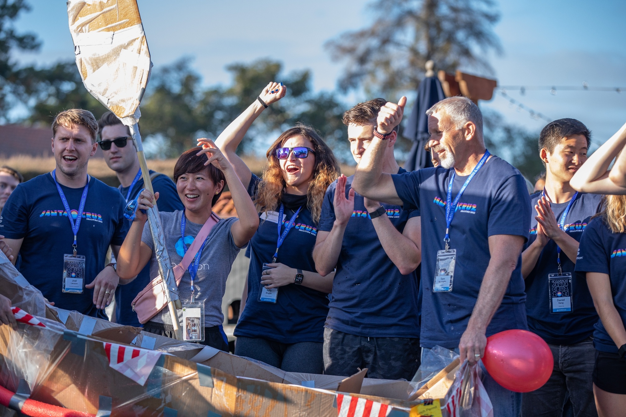 Coalition employees on a team bonding event day, cheering and holding props from the competition.