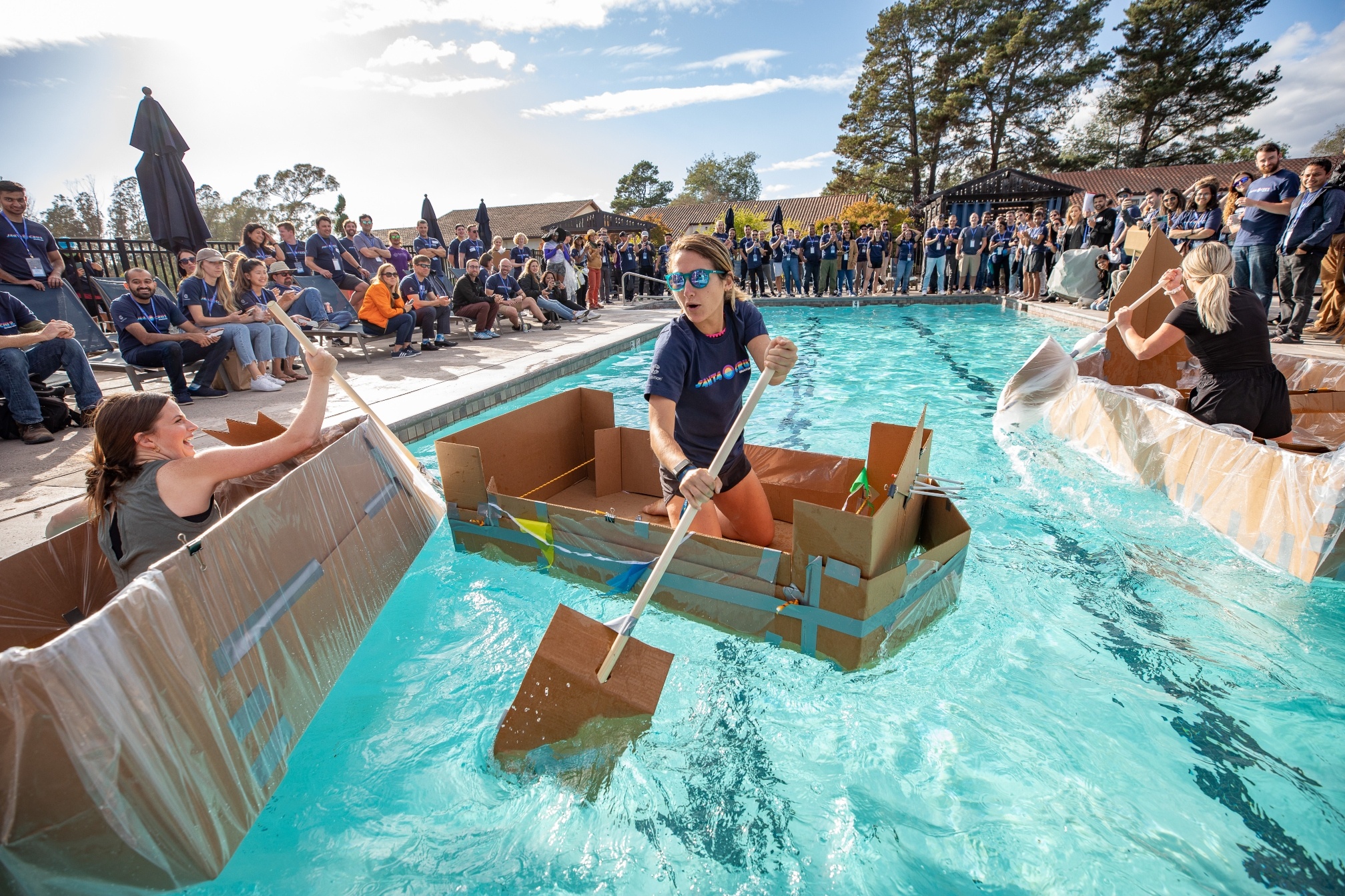 A coalition employee rowing a handmade boat during a team bonding event.