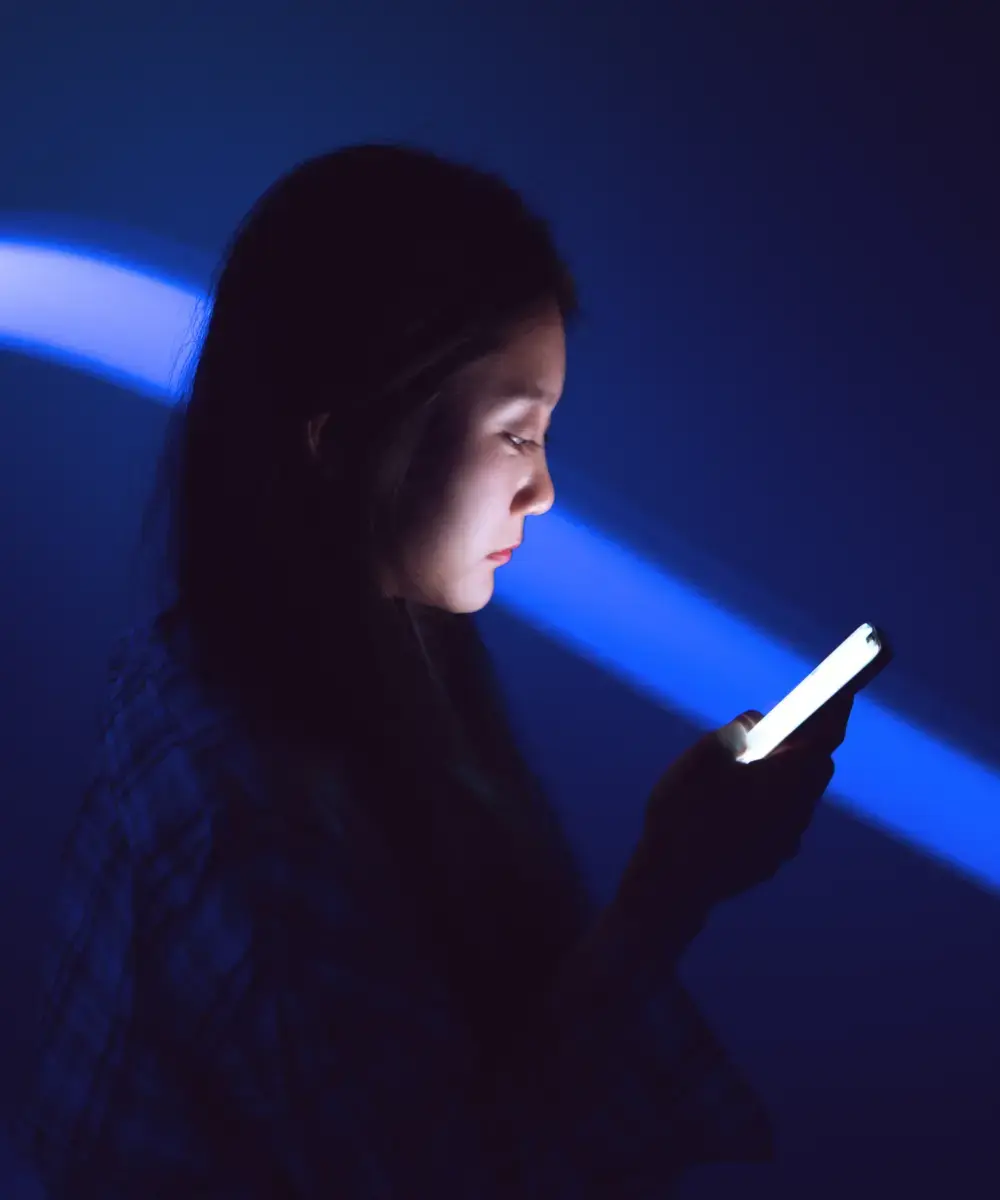 A woman holding their phone in the dark