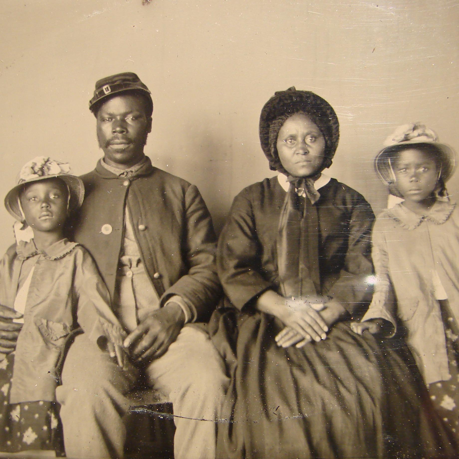 A Black civil war soldier sits with his family for a portrait