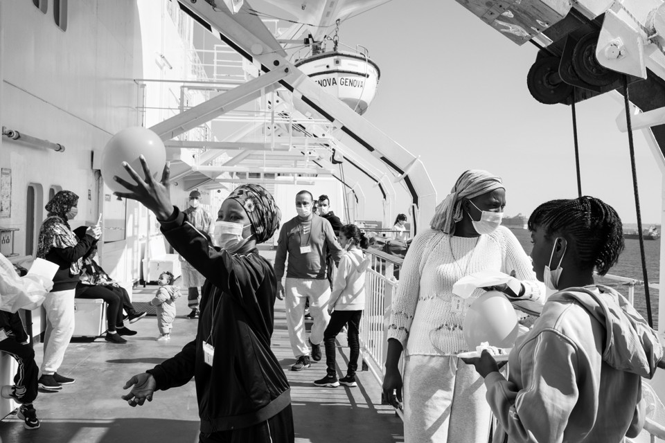 Migrants in face masks on the deck of a ship