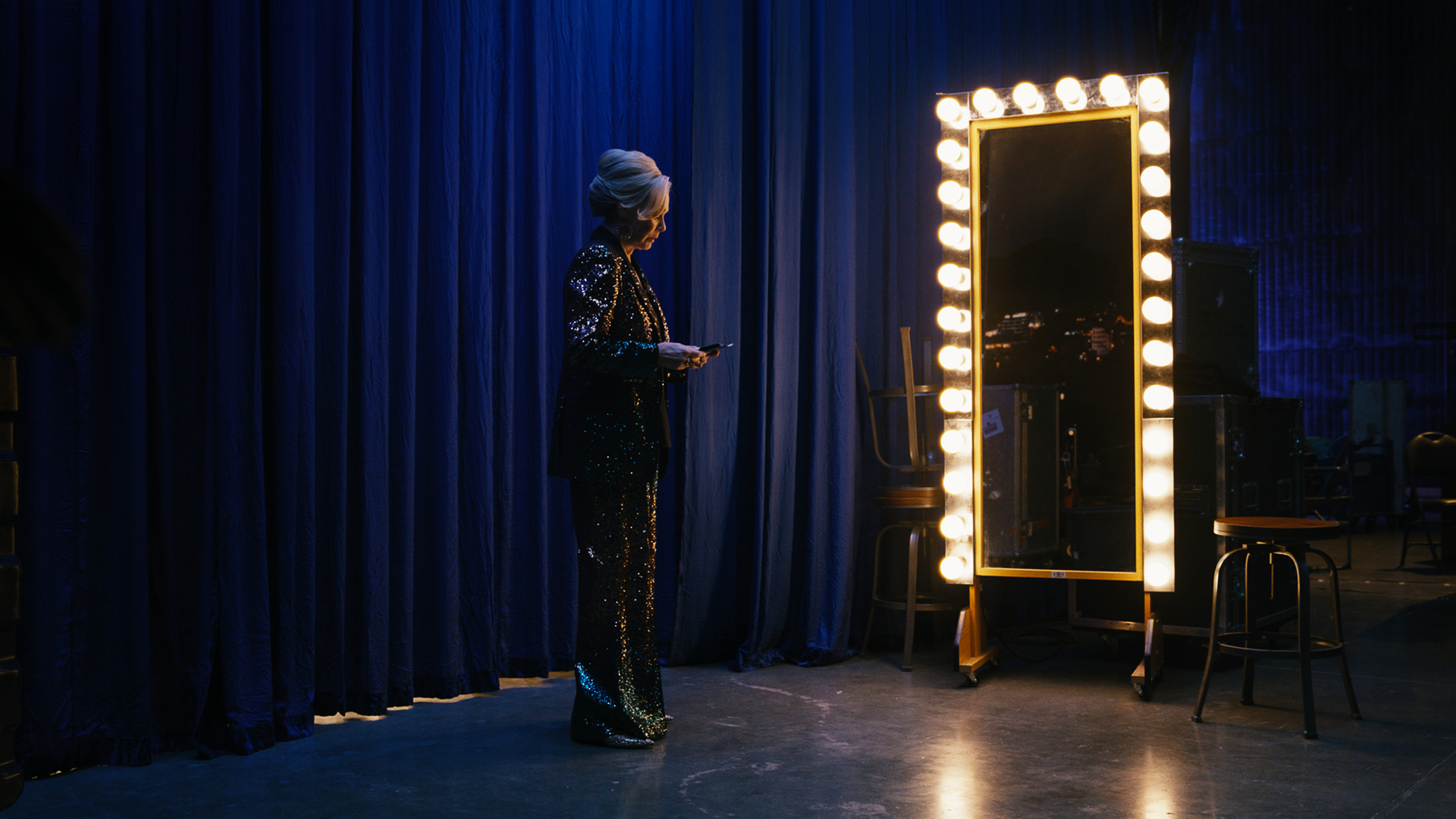 Deborah Vance, in the show Hacks, stands in front of a mirror backstage