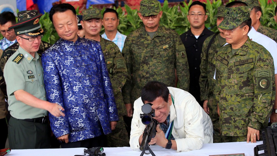 Philippine president Rodrigo Duterte checks the scope of a rifle at a ceremony marking the turnover of free Chinese military assistance to the Philippines at Clark Air Base in June 2017.