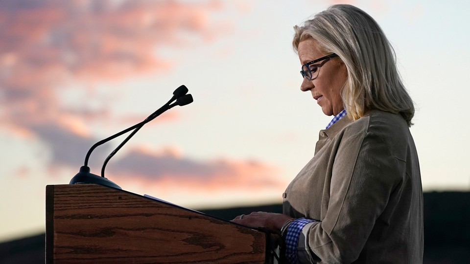 A profile photograph of Liz Cheney standing at a podium, speaking about her future political plans after her 2022 primary defeat