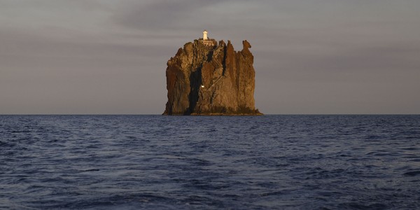 A small isolated island with tall sheer cliffs, topped by a lighthouse