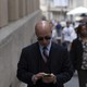 A man checks his phone while walking down a busy street