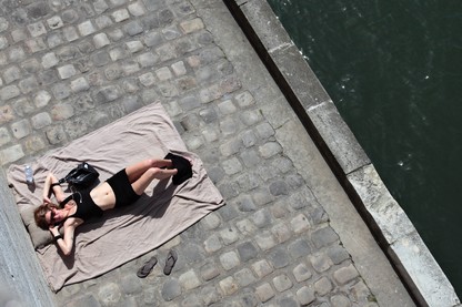 A woman sunbathes next to the Seine river in Paris, France.