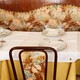 A dining table set with a yellow and white tablecloth, as well as plates and wine glasses