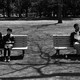 People sitting far apart on benches
