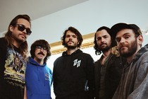 The five members of the band Goose pose for a portrait in their studio.