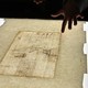 A hand points to a light box with a Da Vinci drawing
