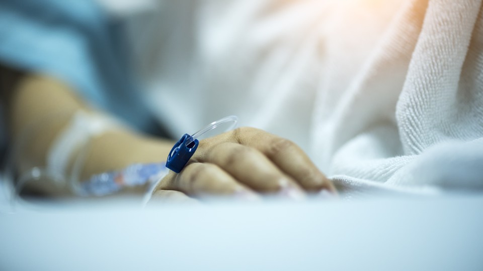 A hand rests on a hospital bed.