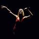 Celine Dion singing with a red leotard over black background