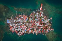 An aerial view of a very small island that is completely covered by houses and small buildings.