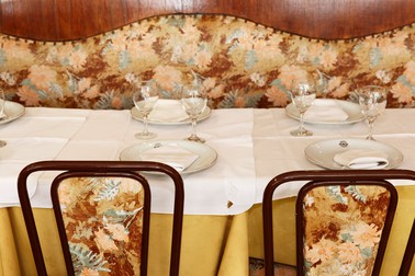 A dining table set with a yellow and white tablecloth, as well as plates and wine glasses