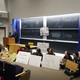 A professor stands at a lecture podium, while protesters sit alongside him holding signs. 