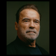 Photo of Arnold Schwarzenegger in dark shirt on green background