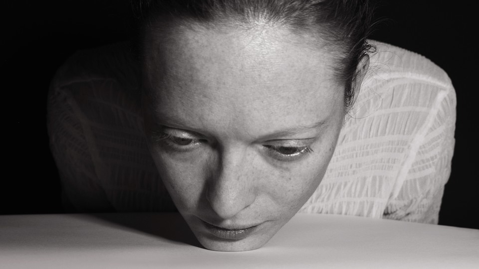 Black-and-white image of a woman placing her chin on the table