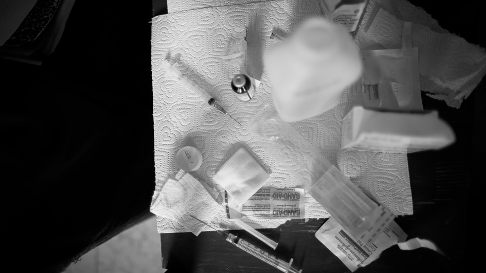 syringes and bandaids splayed out on a paper towel, against a black background