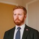 portrait photo of Peter Meijer in suit jacket with blue tie and lapel pin