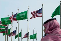 A man stands under American and Saudi flags