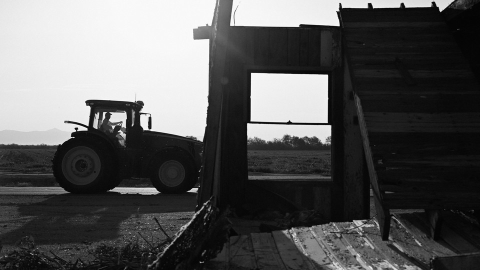 A tractor near a rundown farmhouse