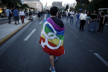 A gay-rights activist wearing a rainbow flag walks through the city center during a Gay Pride parade.