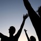 Silhouettes of people praying with their arms stretched up and out