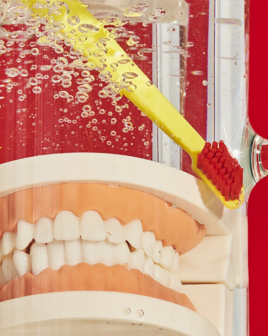 photo of model of teeth and toothbrush in jar