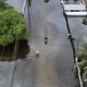 Two people make their way down a street in Miami so flooded that it's essentially a lake.