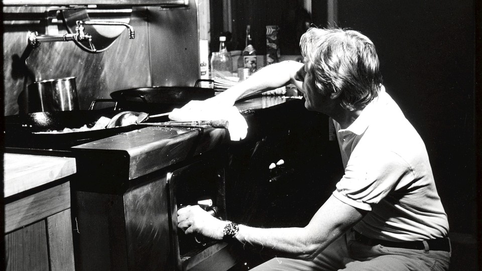 A black-and-white photo of a man cleaning a kitchen