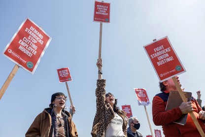 Labor-union organizers holding signs that read, "Rebuild a Fighting Labor Movement!," "Demand Starbucks Stop Cutting Employee Hours!" and "Fight Starbucks' Union Busting!"