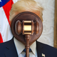 photo-illustration with image of Donald Trump with judge's gavel over his face, with U.S. flag in background