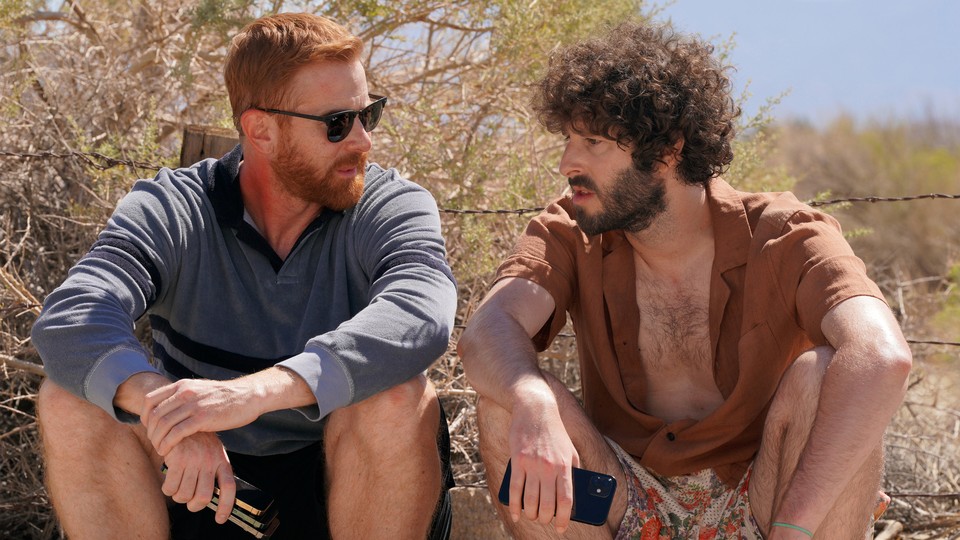 Two men sit on the ground in conversation in a scene from "Dave."