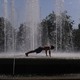 a man doing a pushup in the middle of a large water fountain