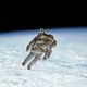 photo of astronaut on spacewalk isolated over luminous curved horizon of Earth against black