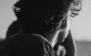 Close-up photograph of a young person staring off into the distance