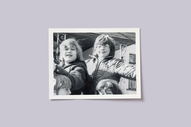 black-and-white photo of two boys sitting near porch, one with glasses