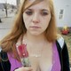 A woman holds a flower in plastic outside.