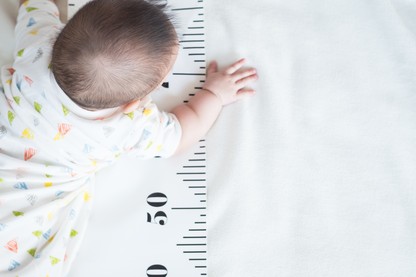 Baby crawling over growth measuring tape