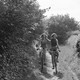 Black-and-white photograph of two people riding bikes down a wooded path