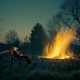 a boy looks up at the sky at dusk while sitting on a bench in front of a large stone fire pit