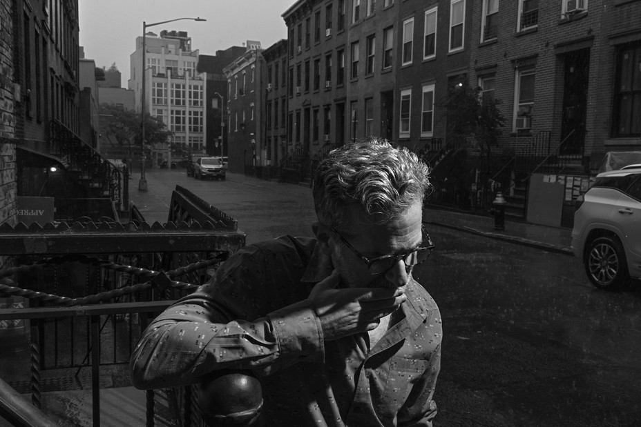 BW image of a man leaning on a fence on a Brooklyn street