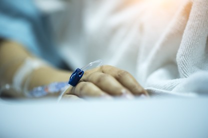 A hand rests on a hospital bed.