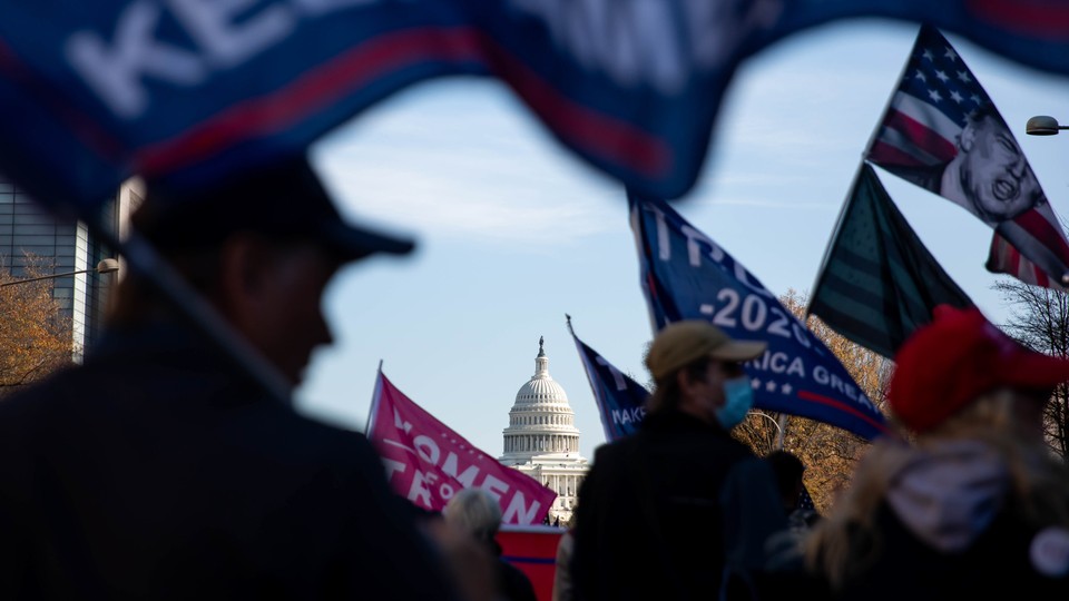 The U.S. Capitol is seen through a group of pro-Trump protesters waving flags on the streets of Washington, D.C.