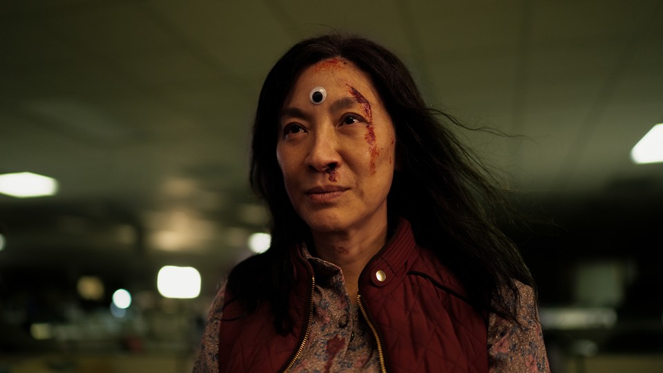 Michelle Yeoh with her face streaked with blood and a googly eye on her forehead