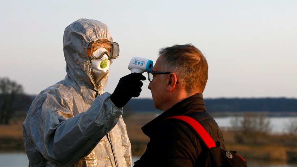 A security agent takes a man's temperature at the Polish-German border.